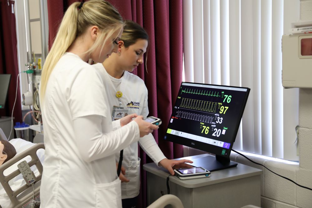 two nursing students looking at vitals screen