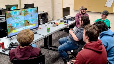 group of students gathered around a computer, playing a game together