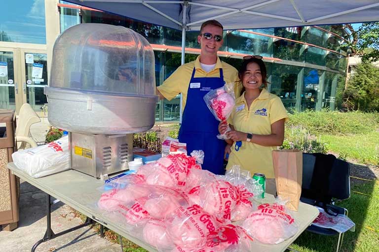 male and female student ambassadors passing out cotton candy at campus event