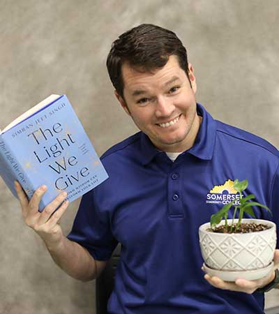 Josh Jones holding a book and a plant
