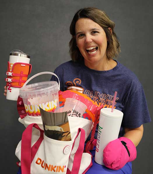Melissa Chmura holding various promotional items from Dunkin Donuts