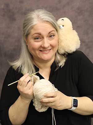 Amy Beaudoin holding knitting supplies and a stuffed sheep
