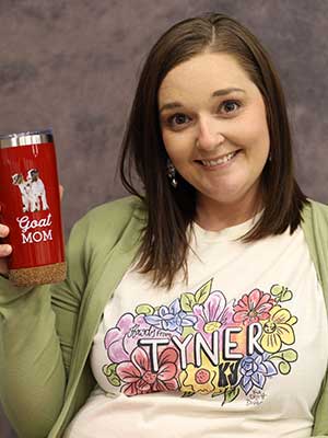 Carla Rose holding a coffee cup that says Goat Mom