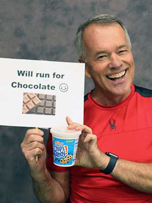 Louie Childers holding a sign that says 'Will run for chocolate'