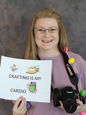 Phyllis Smith holding a camera and a note saying 'Crafting is my cardio'