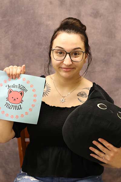 Jillian Wallin holding a cat stuffed animal and a paper that says 'foster kitten mama'