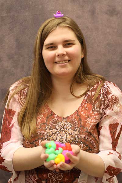 Megan Martin holding small, colorful rubber ducks and a small purple duck on top of her head