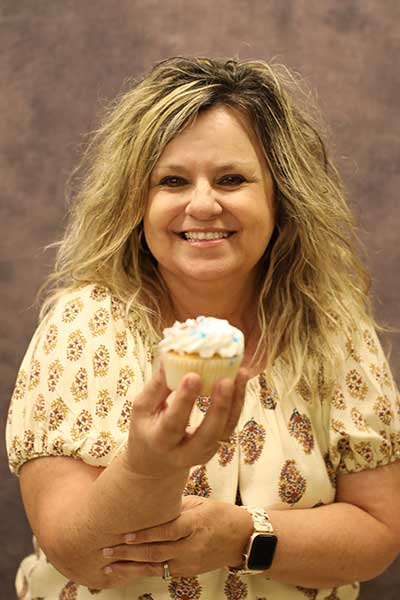 Pam Dean holding out a funfetti cupcake
