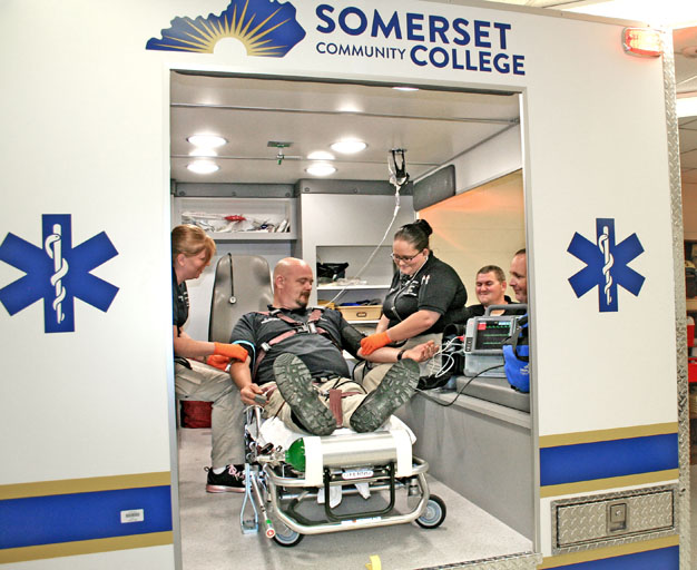students working in ambulance with a patient