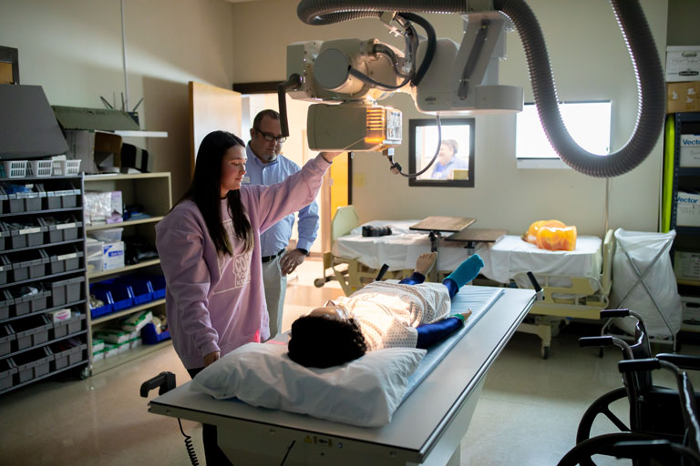 a student and instructor using an x-ray machine on someone