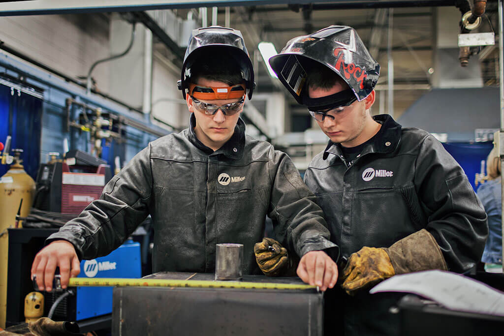 Three welding students being instructed in welding class