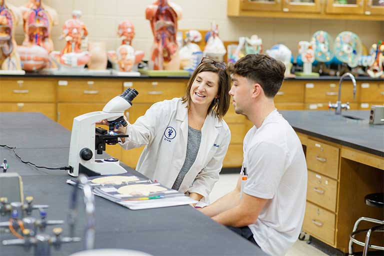 student and instructor using a microscope in the lab