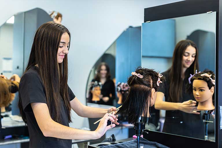 student practicing cutting hair on a mannequin