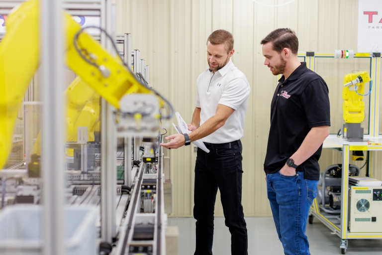 student and instructor looking at a line of machines