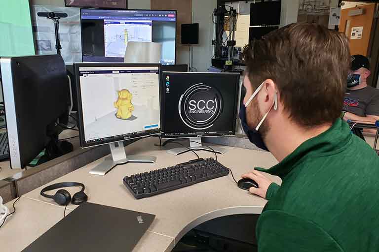 male student wearing a mask on the computer designing a 3d printing model