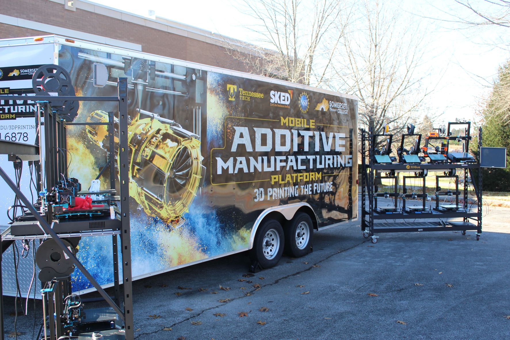 Mobile Additive Manufactoring platform trailer stationed next to several 3d printers