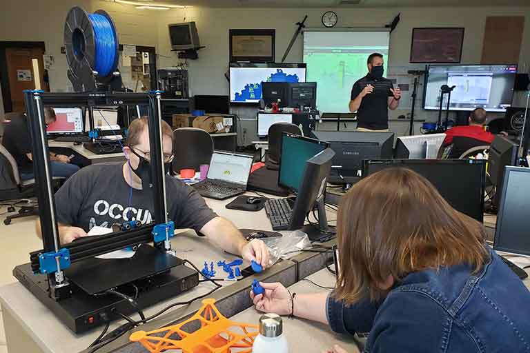 Workshop participants sharing 3D printed pieces after building their 3D printers