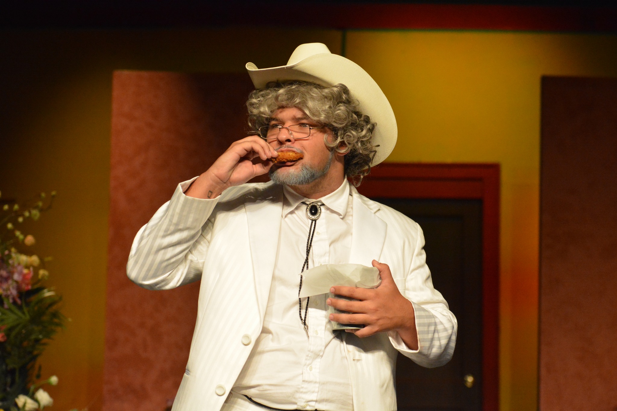 Alvey in a production, dressed in a cowboy hat, white suit, and a bolo tie 