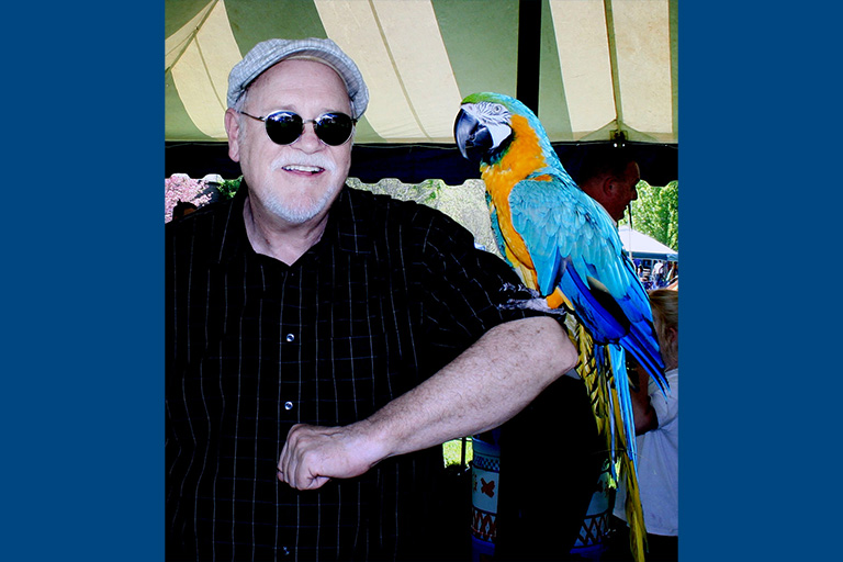 SCC instructor Stuart Simpson with a colorful bird perched on his elbow.