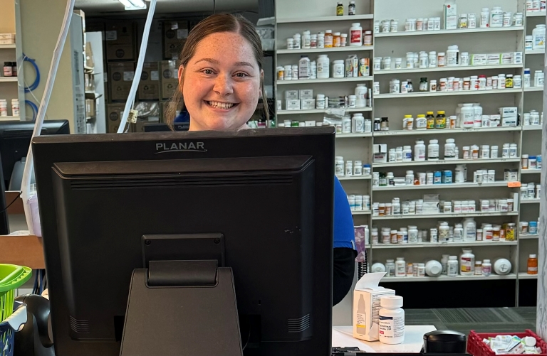 Kylie Hines in a pharmacy, behind a computer