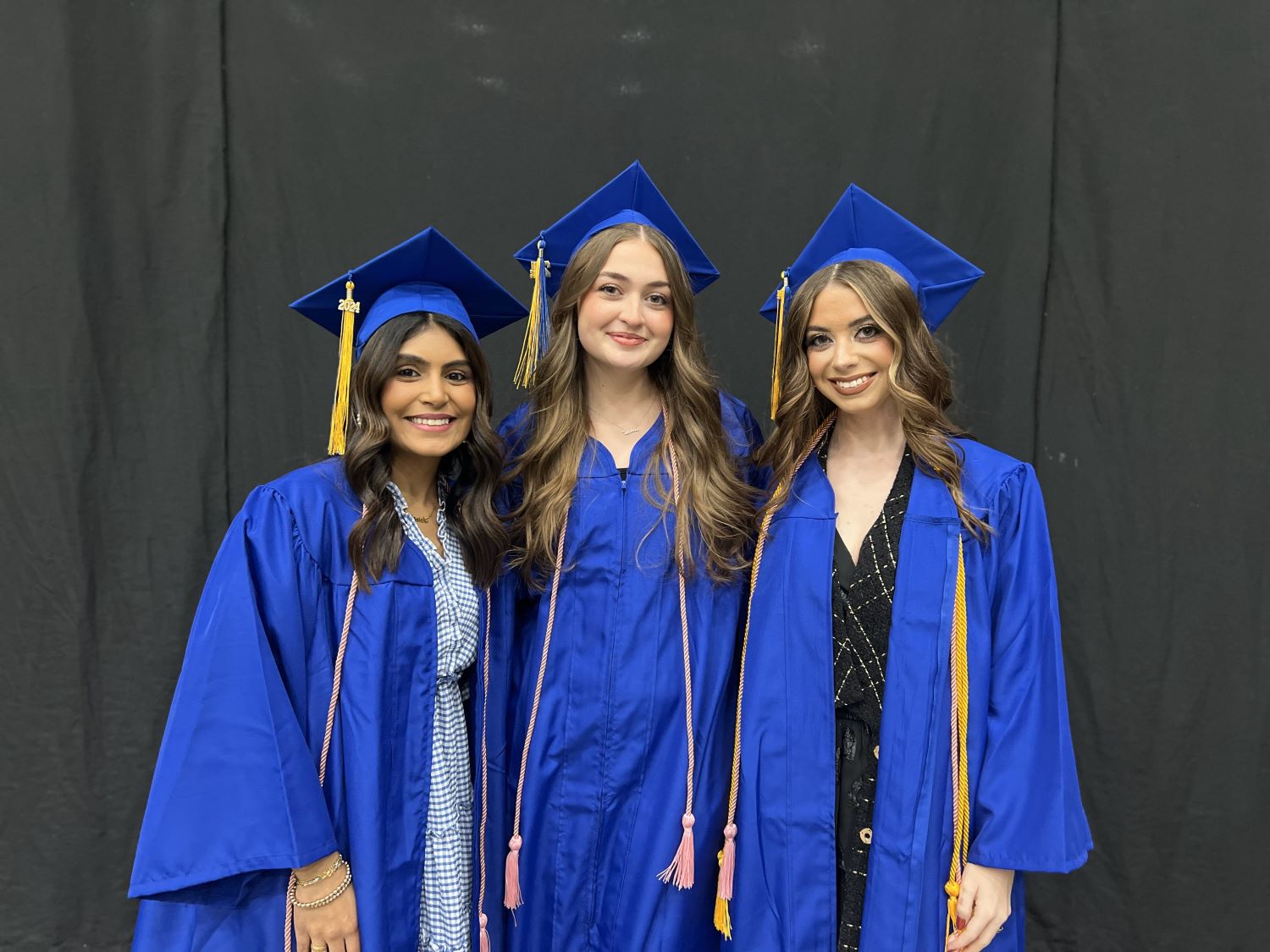 three Cosmetology graduates in graduation regalia