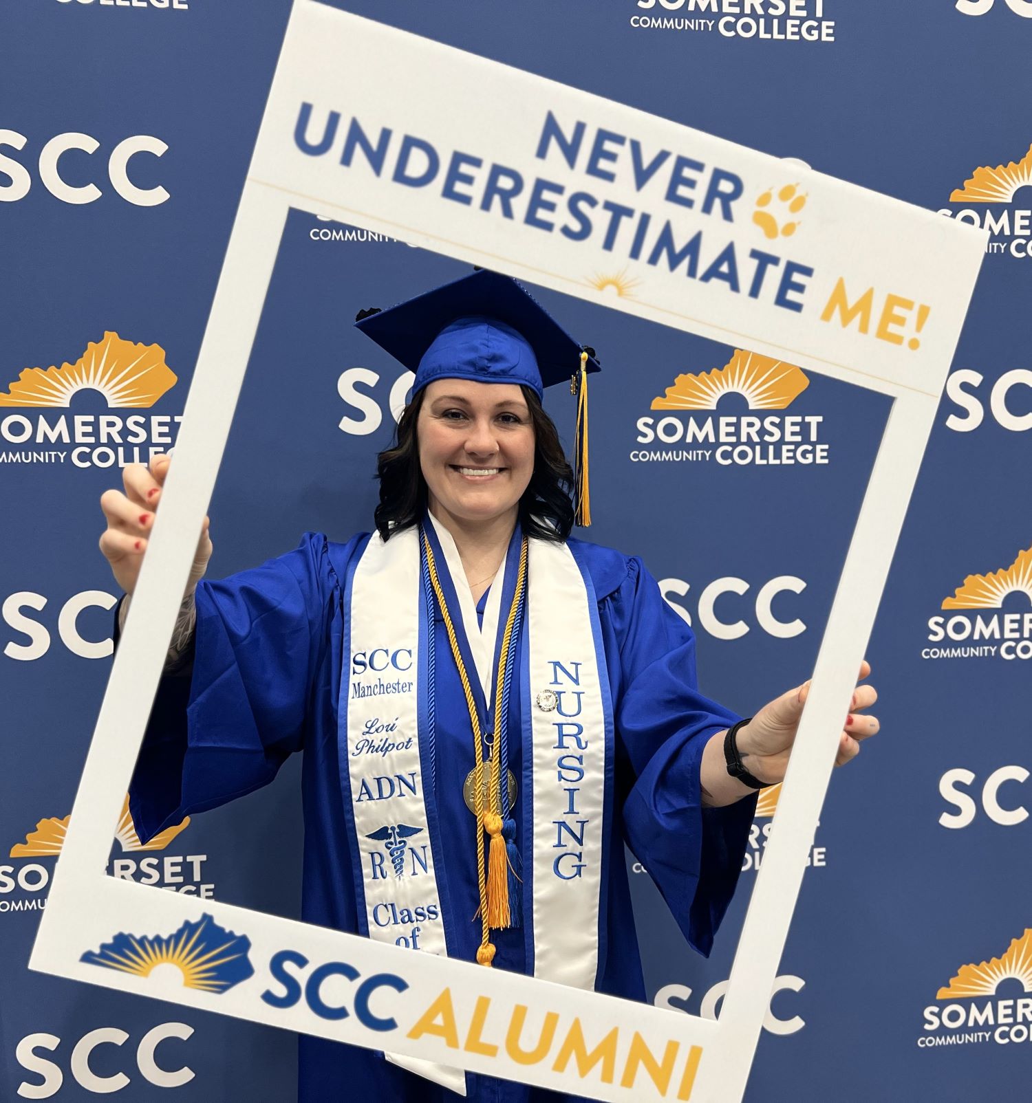 Lori Philpot wearing graduation regalia and holding SCC photo frame