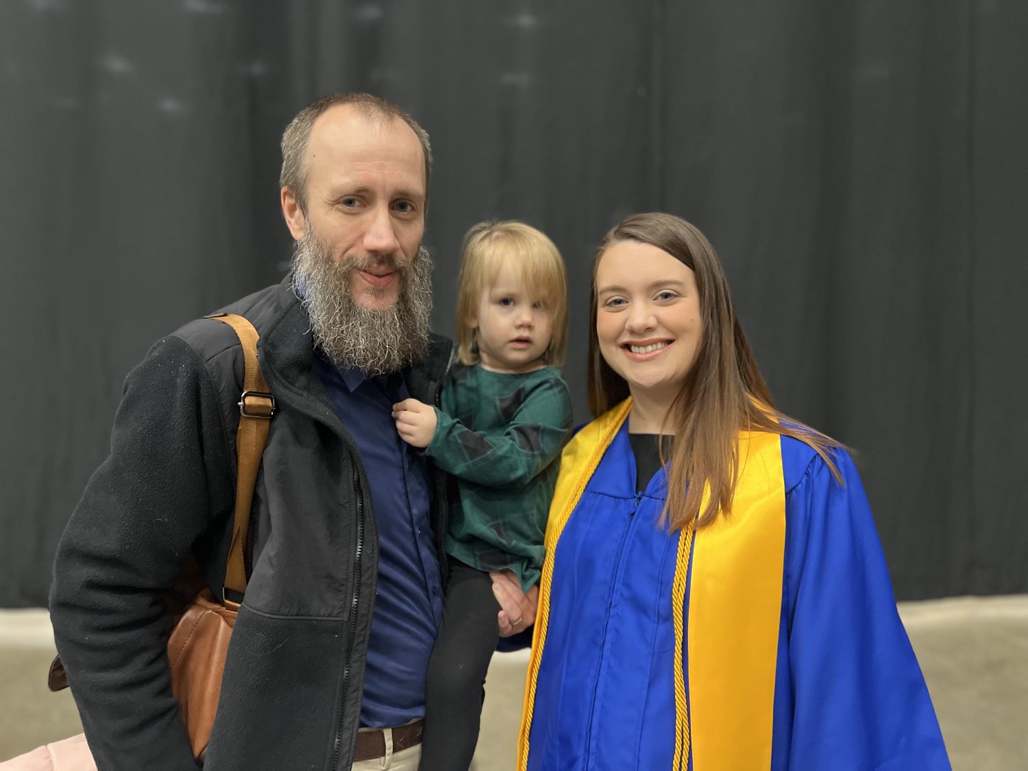 Shelby Pedigo wearing graduation regalia with her family