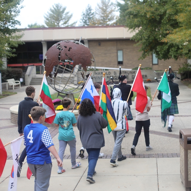 students walking outside and holding international flags