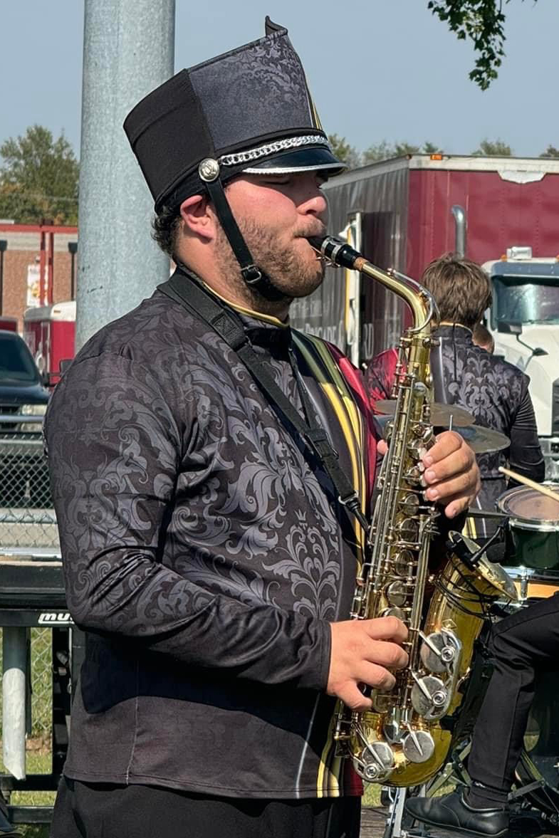 Jordan McCloughan playing a saxophone in marching band gear