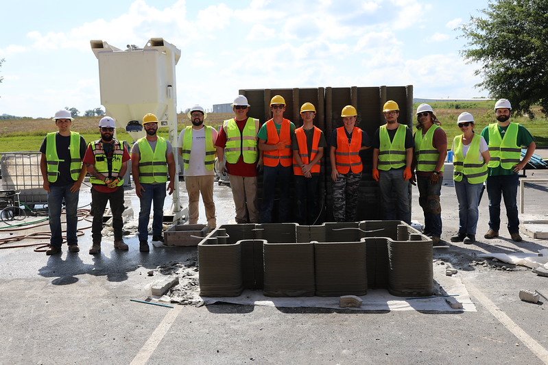 Students with 3d concrete printed house model