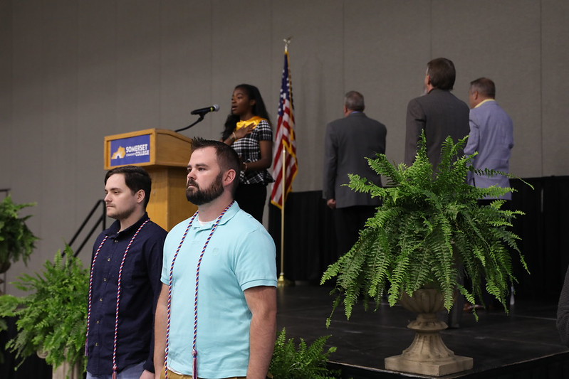 SCC student veterans Jacob Davidson and Cliff Sumler are celebrated with cords in a ceremony as the audience stands for the National Anthem, recognizing their dedication, sacrifice, and remarkable achievements at SCC.