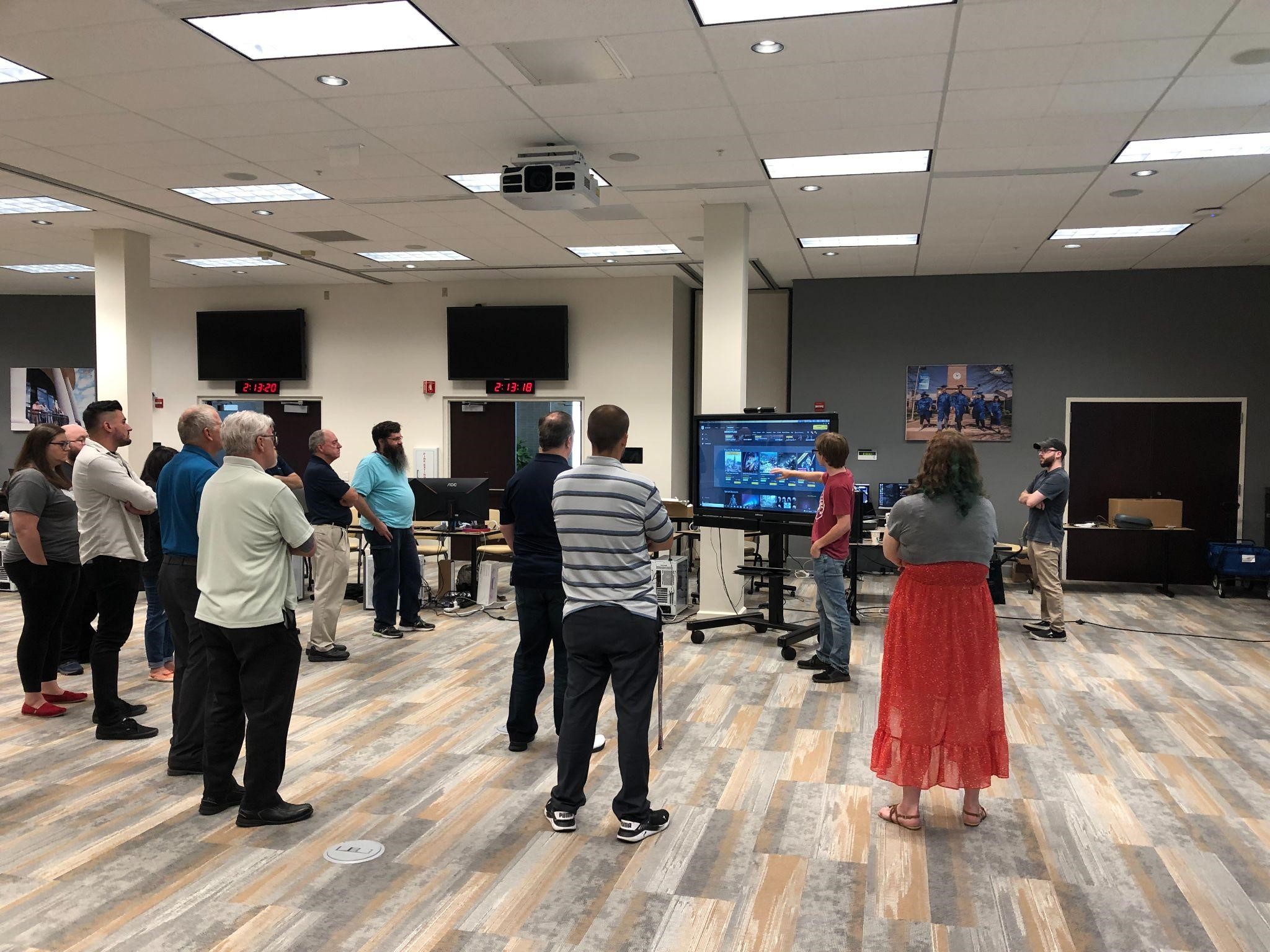 Community College faculty are instructed on how to create 3D models for their VR modules from Low-cost VR project staff. Group standing around monitor.