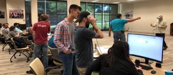 Community College faculty are instructed on how to create 3D models for their VR modules from Low-cost VR project staff. Participants using computers and several wearing VR goggles.